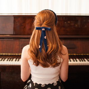 menina ruiva tocando piano com laço no cabelo